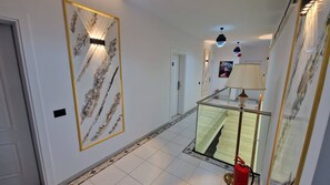 Un couloir avec une rambarde en verre, un extincteur et une œuvre d’art encadrée accrochée au mur.
