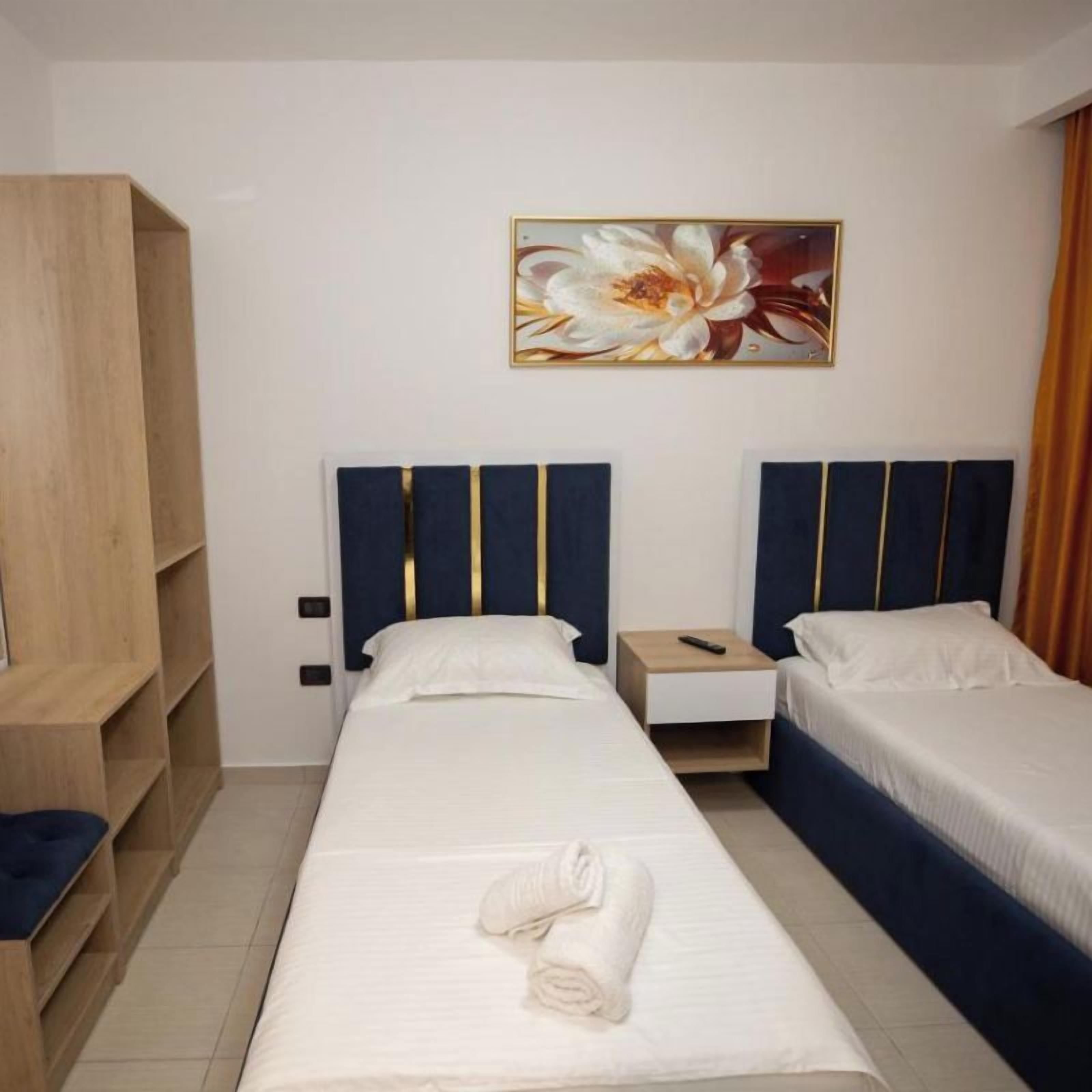 A hotel room with a single bed, a nightstand, a wardrobe, and a painting on the wall.