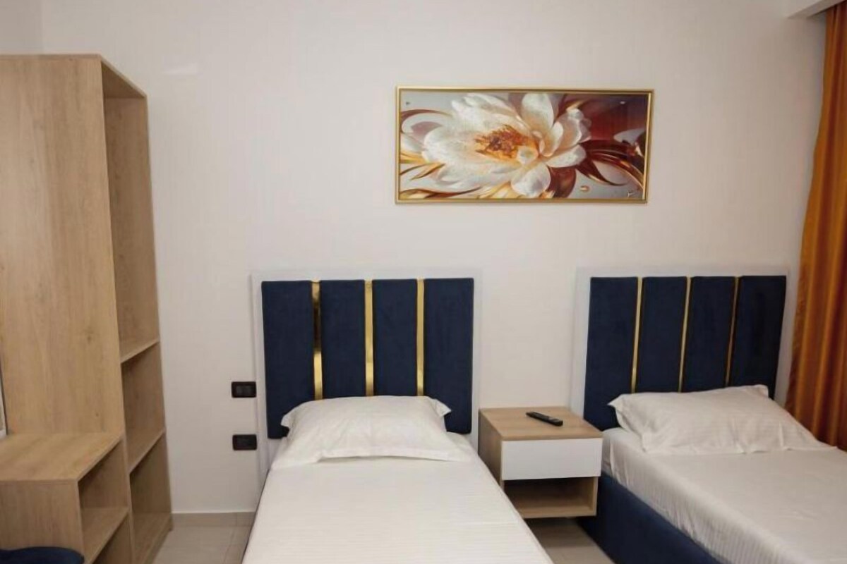 A hotel room with a single bed, a nightstand, a wardrobe, and a painting on the wall.