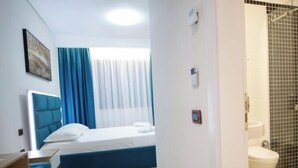 A hotel room with a bed, a desk, a chair, a bathroom with a toilet and shower. - Frekel Hotel (Tirana)