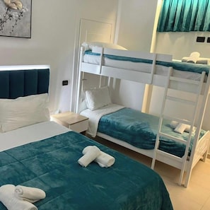 Une chambre d’hôtel avec un lit superposé, un lit simple et une table de chevet.