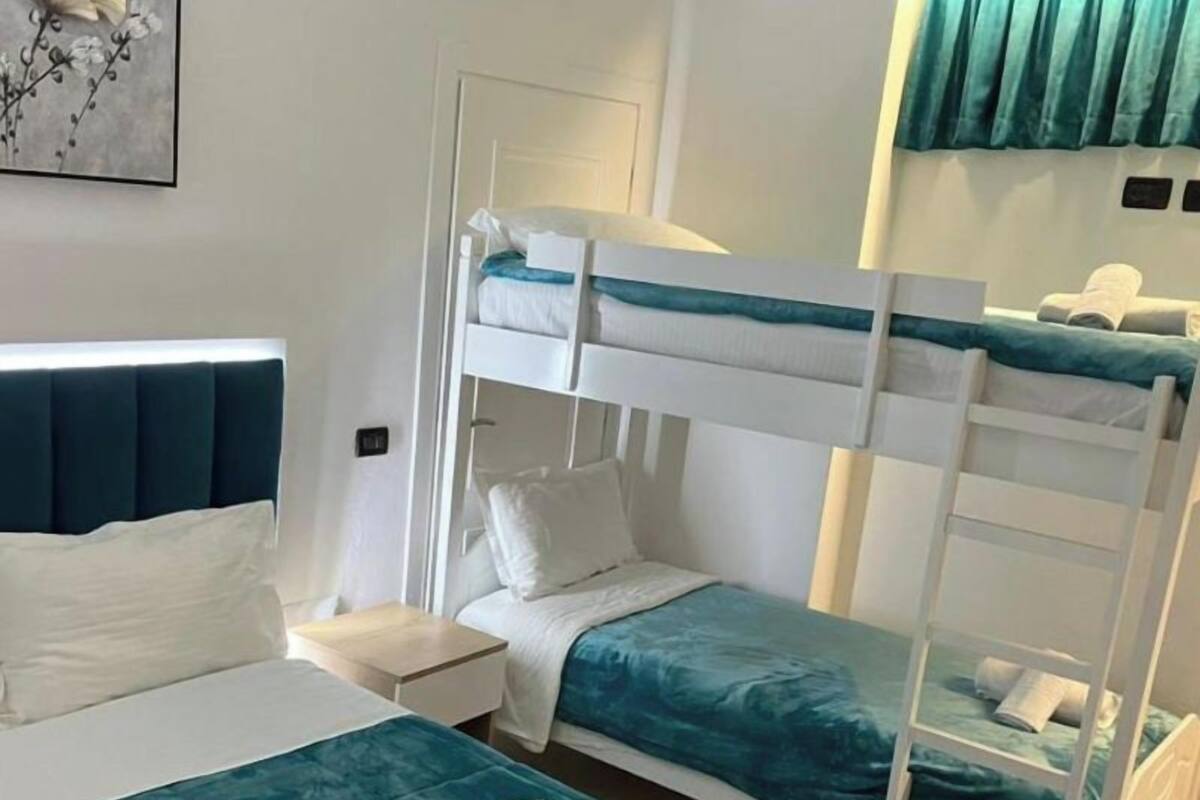 Ein Hotelzimmer mit Etagenbett, Einzelbett und Nachttisch.