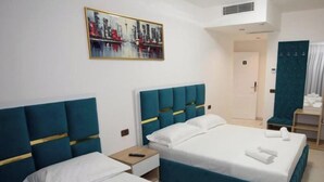 A hotel room with two beds, a painting of a cityscape, and a door leading to another room. - Frekel Hotel (Tirana)