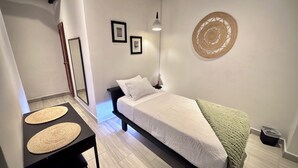 A small, neatly arranged bedroom with a single bed, bedside table, and a wall-mounted light fixture. - Casa Coral Boutique Hotel (Santa Marta)