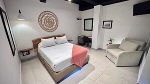A bedroom with a bed, a desk, a chair, and a wall decoration. - Casa Coral Boutique Hotel (Santa Marta)