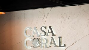 A reception desk with a sign that reads 'CASA CORAL' and a plant on the counter. - Casa Coral Boutique Hotel (Santa Marta)