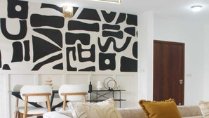 A modern living room with a sofa, two chairs, a coffee table, and a decorative wall piece.