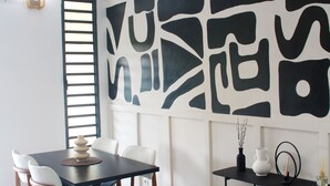 A modern dining area with a black and white abstract wall art, a round table with chairs, and a small side table with a vase and candles.