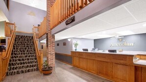 Un'area reception con una scala in legno, una scrivania della reception e un cartello con scritto "American Inn".