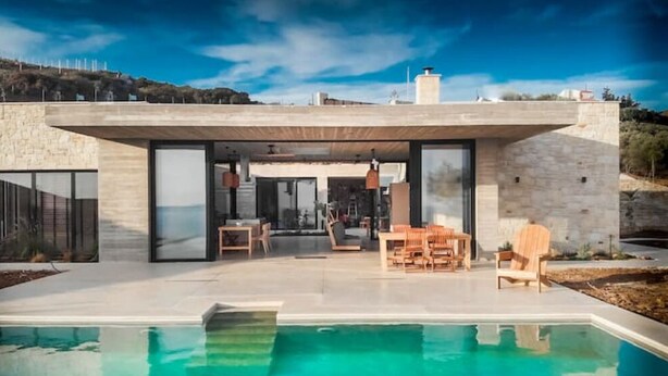 A modern house with a swimming pool, outdoor seating, and a view of the surrounding landscape. - Modern and stylish with sea view (crete)
