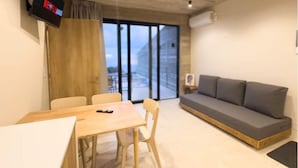 A modern room with a wooden table, two chairs, a gray sofa, and a TV displaying 'Netflix'.