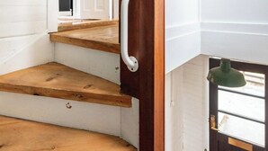A wooden staircase with a handrail, leading to a room with a window and a green lamp. - Elf House in Heart of Downtown Hafnarfjordur (Hafnarfjörður)