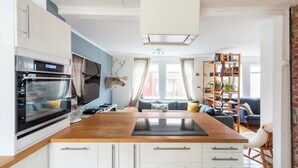 A modern kitchen with white cabinets, a wooden countertop, and a built-in oven. - Elf House in Heart of Downtown Hafnarfjordur (Hafnarfjörður)