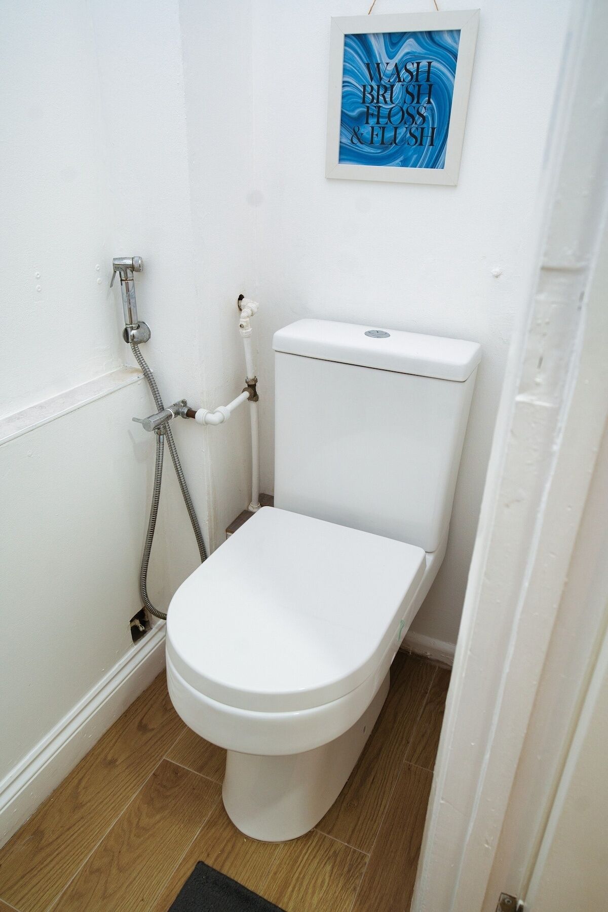 A bathroom with a white toilet, a shower, and a wall-mounted artwork.