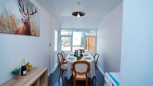 A dining area with a table set for six, a painting of a deer on the wall, and a bottle of champagne on a side table. - Close to city centre home (Bradwell Common)