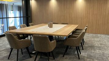 A conference room with a large table, six chairs, and a carpeted floor.