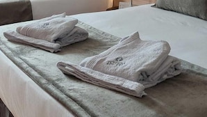 A hotel room with two beds, each with neatly folded towels and a wooden headboard. - Tótem Hotel & Spa (San Martin)