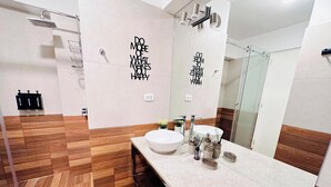 A modern bathroom with a large mirror, a white sink, and a shower area.