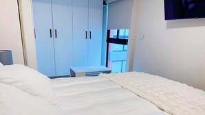 A hotel room with a large bed, a small desk, and a wardrobe.