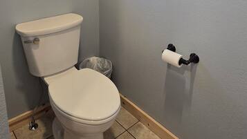 Un baño con un inodoro, una ventana y un portaescobillas en la pared.