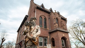 Un gran edificio de ladrillo con ventanas arqueadas y una estatua en la fachada.