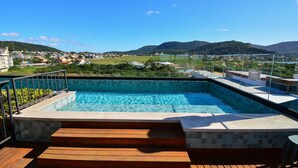 A swimming pool with a view of a town and mountains in the background. - Loft - Haleiwa Novo Campeche (Florianopolis)