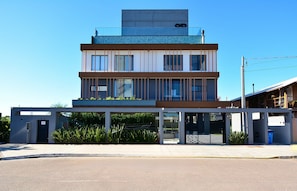 Un edificio moderno de varios pisos con techo plano, ventanas amplias y un área de entrada cubierta.
