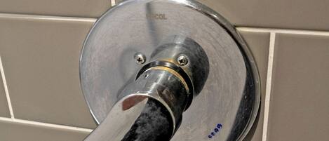 A bathroom with a modern shower control valve mounted on a tiled wall.
