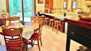 A kitchen with wooden cabinets, a dining table with chairs, and a large island with stools.