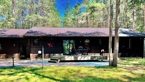 A rustic log cabin with a covered patio, a star decoration, and a small outdoor seating area.