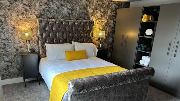 Een slaapkamer met een bed, twee bedlampen, een kledingkast en een vloerbedekking.