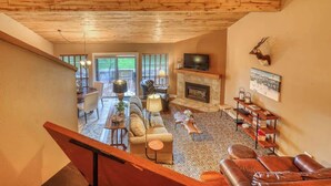Amplia sala de estar con chimenea, sofás de cuero y televisor.