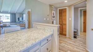 Cucina spaziosa con piano di lavoro in granito, mobili in legno e vista su un'area living con divano e poltrone.