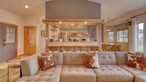 A modern kitchen with a central island, a dining area with chairs, and a large sofa with decorative pillows. - Pet-Friendly Retreat w/ Fenced Yard & Fire Pit (Pagosa Springs)