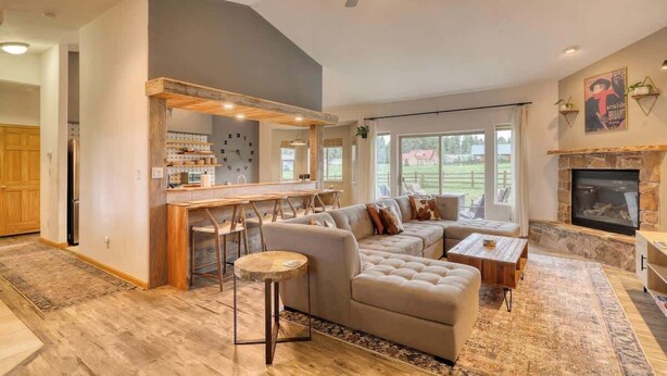 A spacious living room with a large sectional sofa, a fireplace, and a kitchen area with bar stools. - Pet-Friendly Retreat w/ Fenced Yard & Fire Pit (Pagosa Springs)