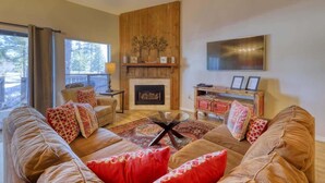 A cozy living room with a fireplace, a large sofa set, and a flat-screen TV mounted on the wall.
