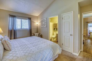 A bedroom with a large bed, a bedside table, a lamp, and a window with curtains. - Bright Townhouse with Sunroom & AC Near Lakes (Pagosa Springs)