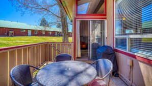 A covered outdoor area with a table and chairs, a grill, and a sliding glass door leading to a covered patio. - Bright 2BR End Unit | A/C + Walkable Location (Pagosa Springs)