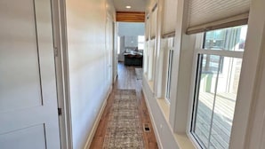 Un couloir doté d’un plancher en bois, de murs blancs et d’un tapis central.