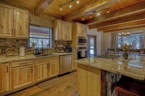 A kitchen with wooden cabinets, granite countertops, and a stone island.