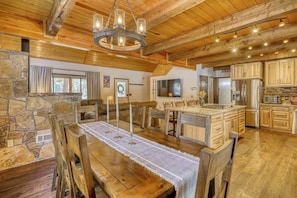 A rustic kitchen with wooden beams, stone walls, and a central island with bar stools.