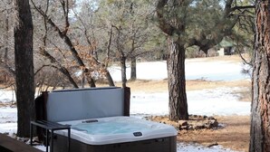A hot tub in a wooded area with a wooden deck. - Golf Course Hot Tub Cabin with Wildlife Views (Pagosa Springs)