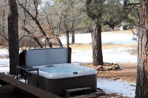 Un bain à remous situé dans un espace boisé, avec une terrasse en bois.