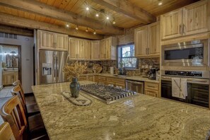 A spacious kitchen with granite countertops, stainless steel appliances, and wooden cabinetry.