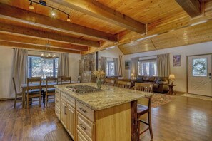 A spacious kitchen with a large island, wooden ceiling beams, and a dining area with a table and chairs. - Golf Course Hot Tub Cabin with Wildlife Views (Pagosa Springs)