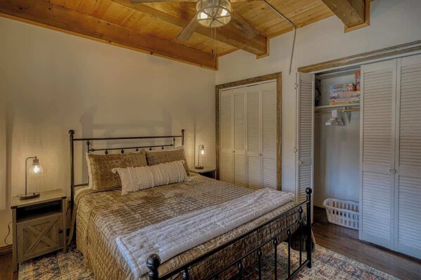Une chambre à coucher avec un lit, des lampes de chevet, un plafond en bois et une armoire avec des portes coulissantes.