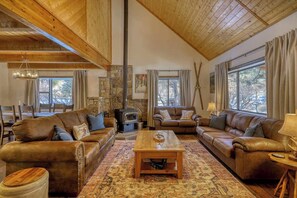 A spacious living room with leather sofas, a wooden coffee table, and a stone fireplace.