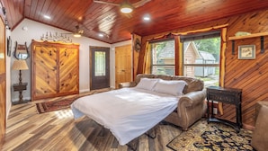 Une chambre confortable avec un plafond en bois, un lit, une fenêtre et une porte.
