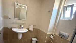 Une salle de bain équipée d’un lavabo, d’un miroir, de toilettes et d’une douche.