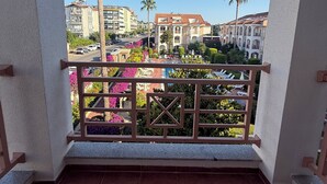 Un balcon donnant sur un quartier résidentiel, avec vue sur des immeubles et des palmiers.
